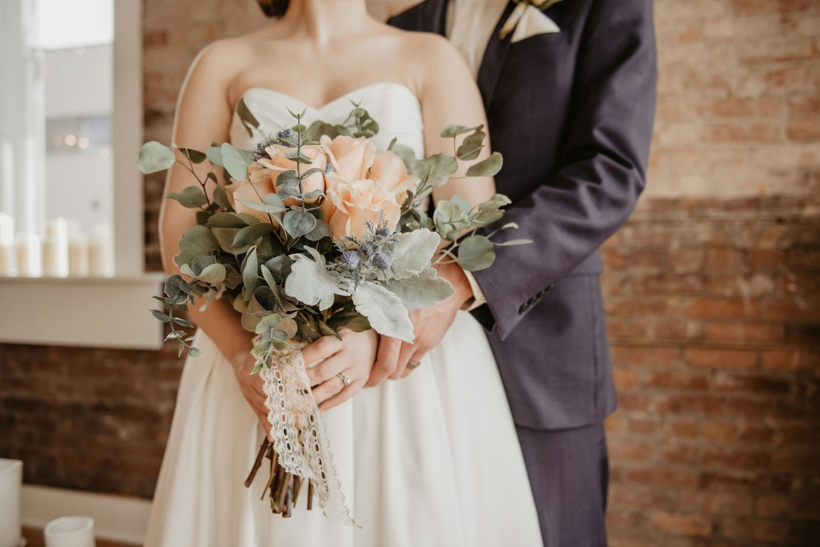 Bride and groom close together, bridal bouquet in focus